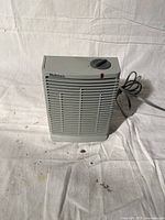 Front view of a grey Holmes electric space heater showing vent slats, brand label, rotary dial and power cord.