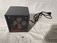 Front view of The Heat Machine black space heater showing mesh grill and heating elements.
