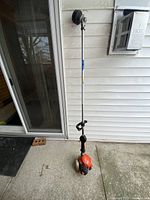 Full view of the wipper snipper showing the straight shaft and orange engine assembly.