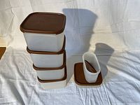 Six Tupperware Modular Mates plastic storage containers with brown lids arranged on a white background: stacked containers on left, one oval container and one lid on right