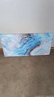 Horizontal abstract art canvas wrapped in plastic leaning against wall