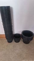 Photo of tall stack of 48 black 5-inch net pots next to smaller stacks of 3 six-inch and 8 eight-inch net pots.