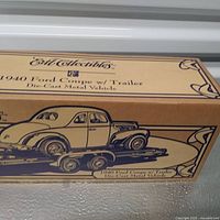 Photo of brown cardboard box packaging with blue illustration and text labeling the 1940 Ford Coupe with trailer die-cast vehicle by Ertl Collectibles.