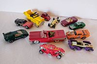 Photo showing the full collection of 11 vintage die-cast model cars including various colors and models such as the yellow dump truck, purple/green Shredster, red convertible, orange muscle car, and others.