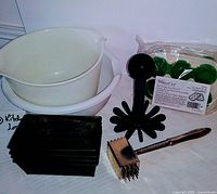 Photo showing two white mixing bowls stacked, four small black rectangular loaf pans, metal meat tenderizer mallet, black multi masher, and Pampered Chef Garden Herb Freezing Trays in package.