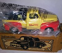 Side view of the 1951 Ford Pickup Truck die-cast model in original plastic wrap and box showing yellow and red paint and Mac Tools branding.
