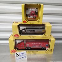 Three boxed Mac Tools Racing die cast vehicles stacked for display: red Jeff Shepard sprint car, black and gray Penske Racing truck, red Budweiser King tractor trailer.