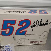 Box showing the number 52 and signature with Morema Inc. branding and airplane illustration