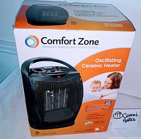 Black Comfort Zone oscillating ceramic heater with orange and white box showing front view and product details.
