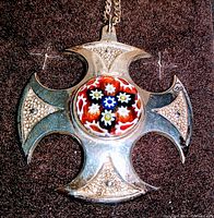 Front view of the sterling silver Maltese cross pendant showing granulated texture and Millefiori glass center.