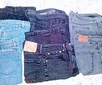 Overview photo showing all 7 pairs of jeans in black and denim blue colors folded and arranged for display.