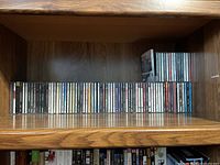 Shelf with approximately 45 music CDs vertically arranged