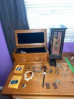Full overview of lot including two jewelry boxes, various bracelets, earrings, necklaces, and watches arranged on table.