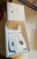 Sealed box of Apple EarPods with Lightning connector on top of open empty box.
