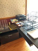 Overview photo showing black Epson Workforce WF-2630 color printer on table with assorted office supplies including clear plastic magazine holders, hanging file folders, calculator, and black multi-tier desk organizer rack.