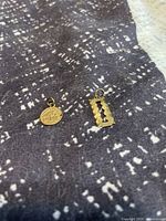 Photo of two gold pendants on fabric: round graduation pendant and razor blade shaped pendant.