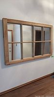 Front view showing pine wood frame divided into six mirror sections, hung on wall.