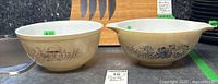 Photo shows both Pyrex bowls side by side, highlighting the Homestead Blue 11-inch and Forest Fancies 8.75-inch patterns and sizes