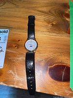 Full view of the Seiko wristwatch laid flat on a wooden surface, showing the watch face and black strap.