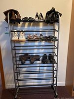 Photo of 10-tier metal shoe rack with arranged shoes including women's boots, sneakers, sandals, and men's shoes on the shelves.