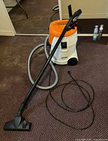 Full view of the Stihl SE 62 shop vacuum with hose and floor nozzle attachment connected, placed on carpet.