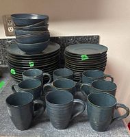 Stacked dishes and bowls with mugs in front showing details of glaze and color.