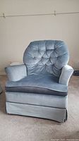 Front view of the light blue velvet armchair showing the tufted backrest, padded arms, and removable seat cushion.