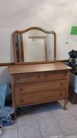 Front view of wood dresser with mirror perched on top