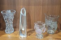 Set of four crystal vases grouped together on wooden surface