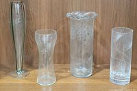Front view of all four vases showing their shape and etched patterns