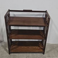 Front view of wooden 3-tier folding bookshelf showing shelf surface and frame design