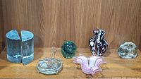Full view of all seven glass items showing bookends, pitcher, paperweight, sun catcher, flower petal candleholder and clear candleholder