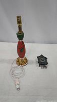 Photo showing entire table lamp and mini cuckoo clock side by side, electrical cord and plug visible