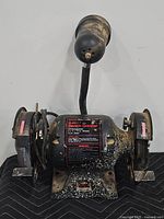 Front view of Sears Craftsman bench grinder showing double wheels, power switch, and attached lamp.