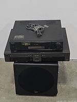 Sony SLV-720HF VCR and Go-Video dual deck VCR stacked on KLH subwoofer showing front views and model details