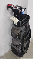Side view of the black and gray Callaway staff caddy golf bag showing front zippered pockets and club heads with head covers.