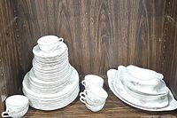 Full view of stacked Haviland china including cups, plates, platters, and gravy boat with visible floral pattern and scalloped edges.
