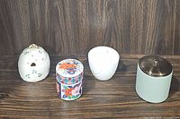 Set of four lidded dishes arranged side by side showing variety in colors and shapes.