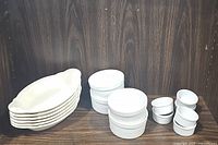 Shows all items: 6 white oval boat baking dishes stacked on the left; 4 Pier 1 ribbed ramekin dishes in the middle; 6 smaller plain white ramekin dishes on the right