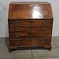 Front view, drop-front closed, showing three lower drawers with brass bail handles