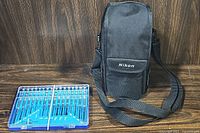 Nikon carrying case with shoulder strap beside precision screwdriver set in blue plastic case.