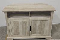 Front view of the farmhouse style TV stand showing two closed cabinet doors and an open shelf above them.