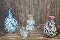 All four unique decorative vases shown together on wood surface with wood panel background