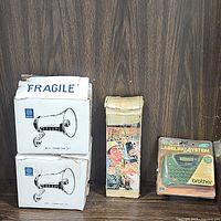 Pair of boxed Fanon public address loudspeakers, each with 6 inch bell diameter and marked fragile, along with vintage Realistic TRC-99C CB radio in carrying case and new Brother P-Touch labeler in packaging.