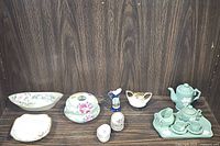 Full lot showing all items on wooden shelf: miniature tea set pieces on right, trinket dishes, white pearl pitcher, and other small porcelain items on left and center.