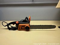 WEN 16-inch electric chainsaw placed on a table showing the full length of the saw and blade.