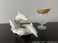 Photo showing the ceramic beluga whale pod sculpture alongside the blown glass candy dish from the side.