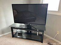 TV stand under a Samsung TV; top view showing black tempered glass surface with metal frame