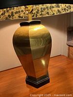 Close-up of the shiny brass lamp base with hexagonal shape on a wooden surface