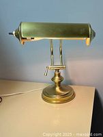 Front view of brass piano lamp showing tubular light head and vertical double stem on round base.